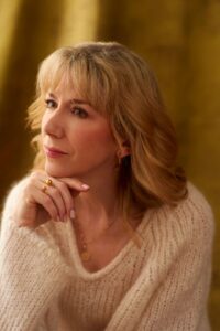 Irish singer Muireann Nic Amhlaoibh in a cream jumper looking to one side, her hands under her chin