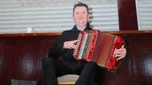 Irish Musician Gary Curley of Chunky Business playing a red accordion