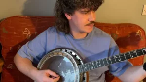 Irish musician Stephen McKee from Chunky Business playing the Banjo in a blue t shirt