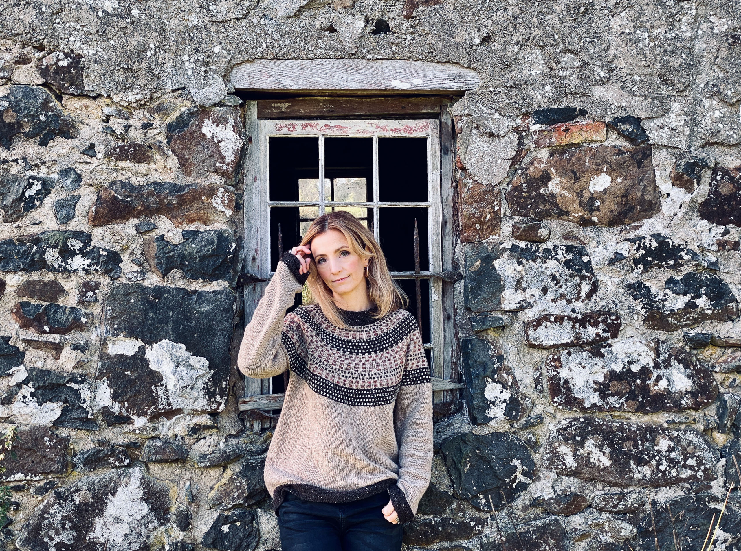 Irish singer Cara Dillon Coming Home album photo in a jumper in front of stone house