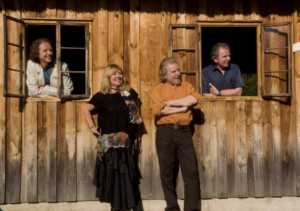 Photo of the Sands family band 3 men 1 women standing by a wooden house