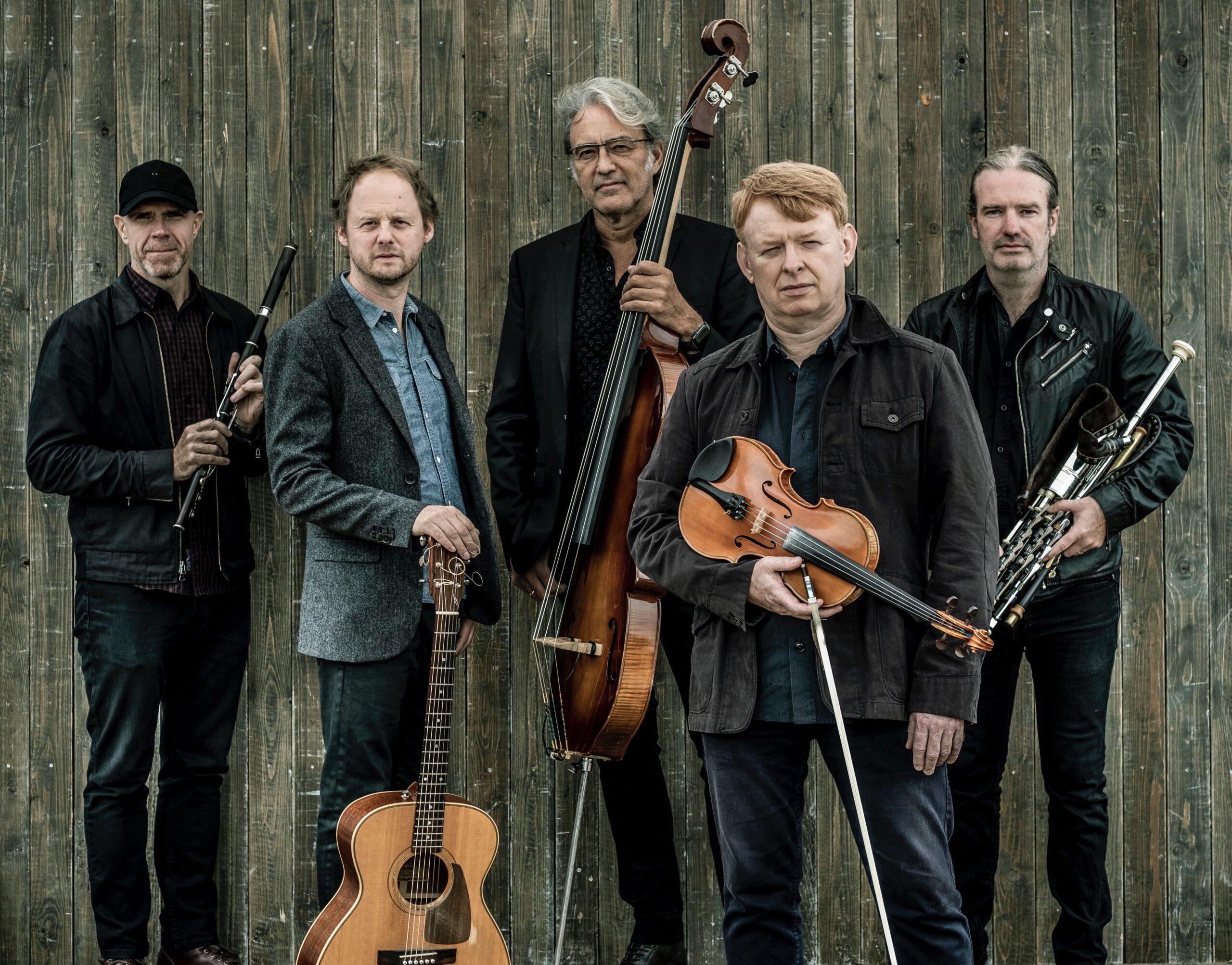 All male Irish band Lúnasa with their instruments looking at the camera with jackets and shirts on