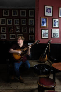 contemporary Irish folk musician Macdara Yeates sat playing guitar in pub